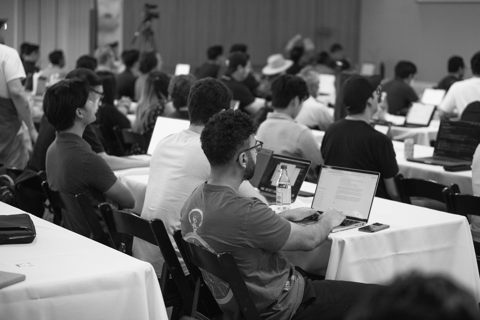 A packed Claude workshop in Tustin, Orange County: attendees at long tables with laptops open, one man in the foreground typing into Claude.